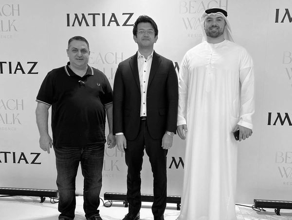 Three men posing at an event with IMTIAZ and Beach Walk Residence branding.