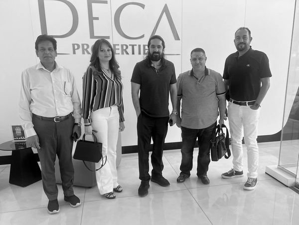 Five professionals posing together at DECA Properties office.